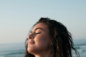 Woman with closed eyes and wet hair at the beach.